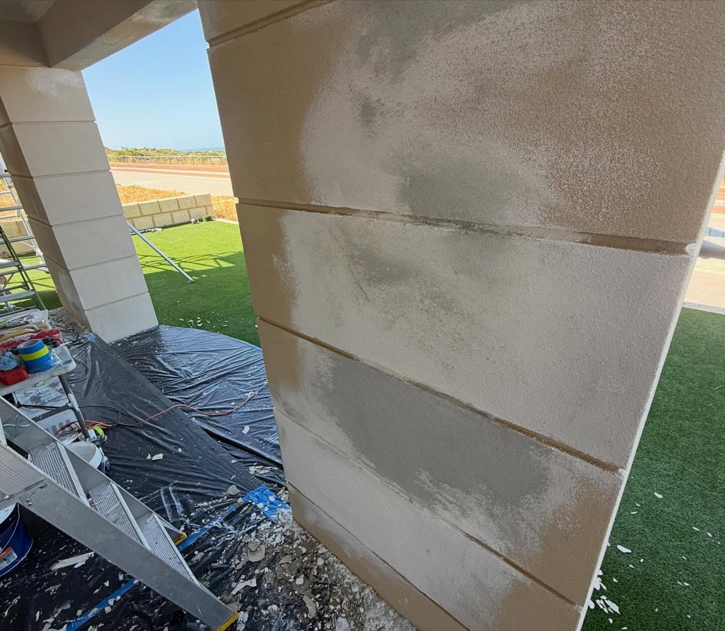 Rendered wall patched and prepared, with drop sheets and painting gear laid out ready for coating